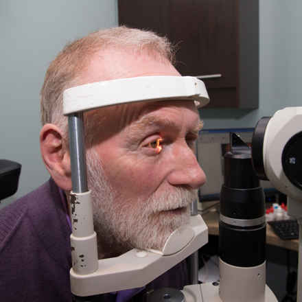 Older man having his eye checked, with light on his right eye