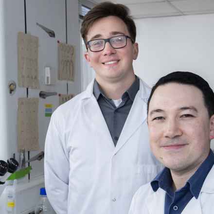 Professor Chu and PhD student Kuba in the research lab smiling to camera