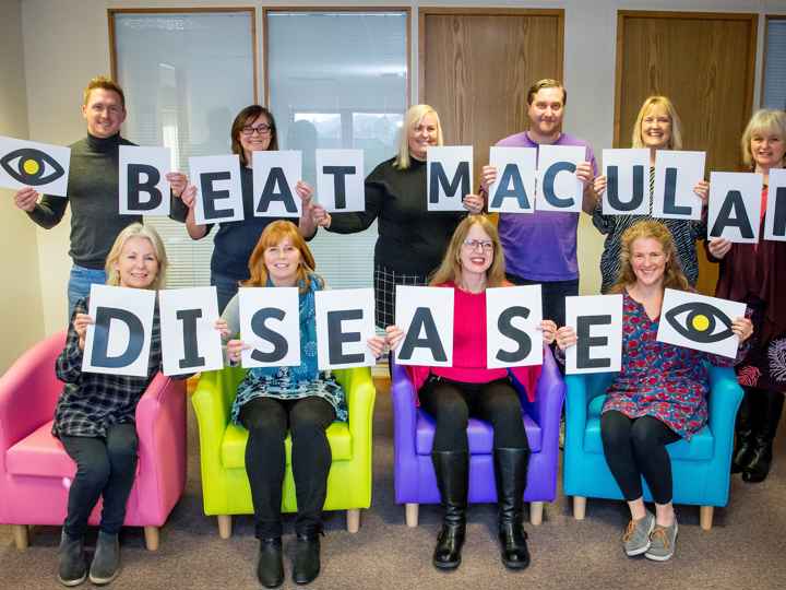 Macular Society staff holding up Beat Macular Disease cards