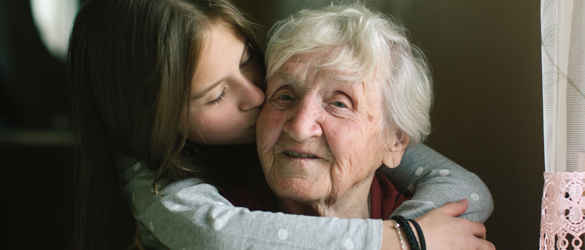 grandmother and granddaughter hugging and kissing cheak