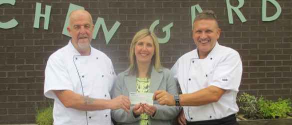 three individuals holding a cheque