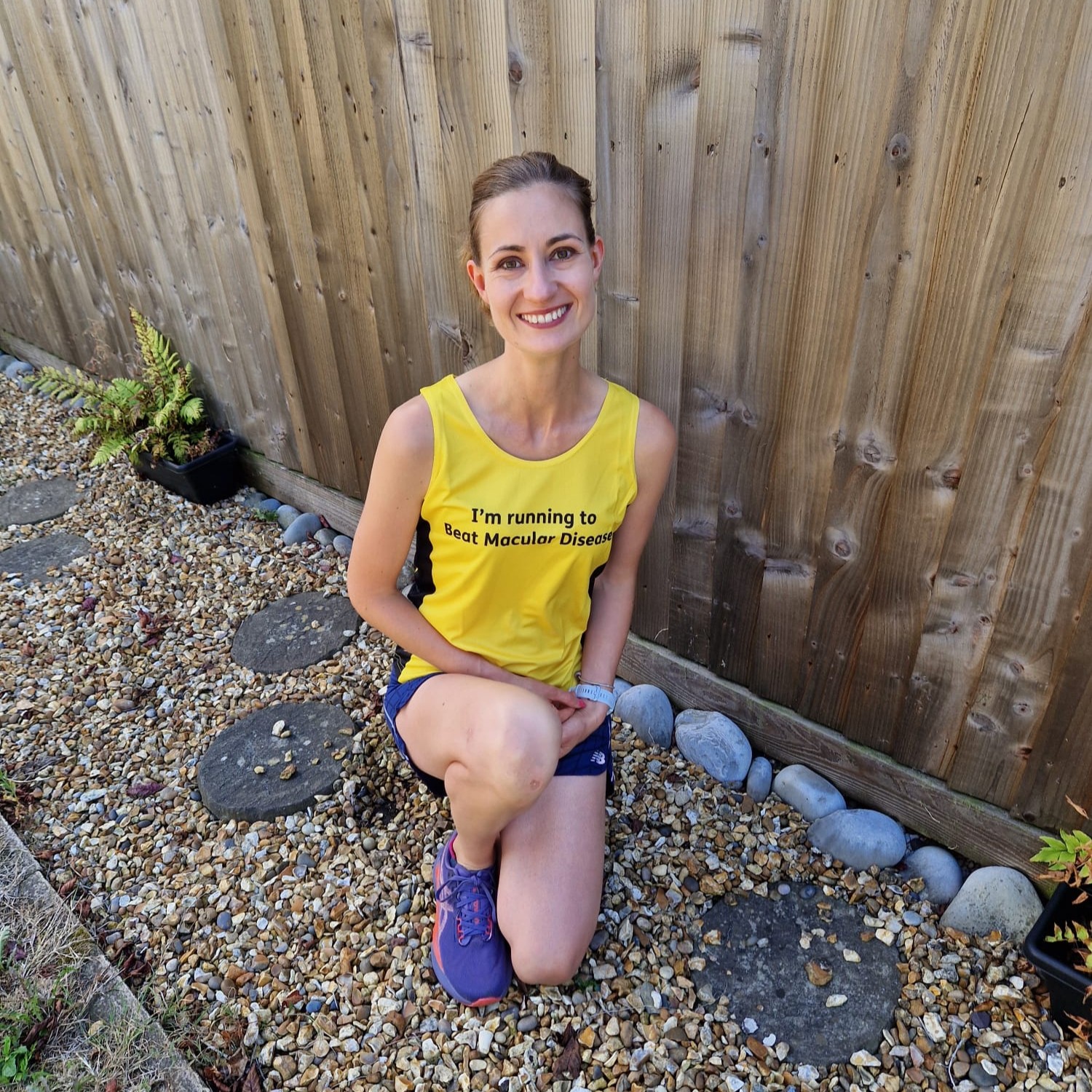 Lucy crouches down dressed in her yellow Macular Society fundraising t-shirt.