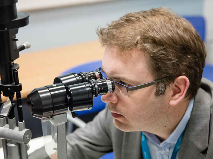 Pearse Keane looking into a microscope