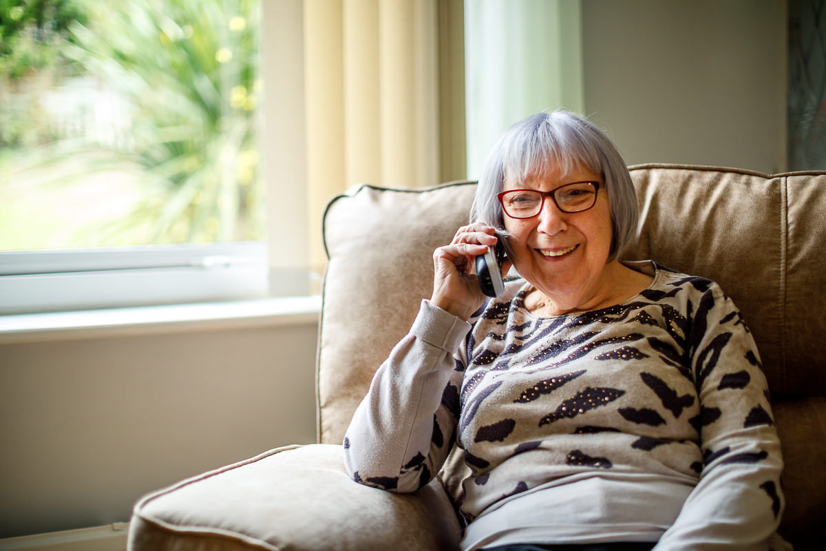 Volunteer, Audrey Drage smiling on the phone