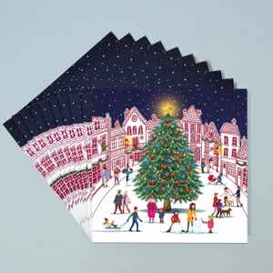 A stack of 10 greeting cards with a festive illustration of a beautiful Christmas tree in the middle of a town square as families enjoy the snow