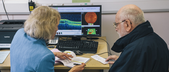 Female consultant, discussing results with male patient with computer images of results.