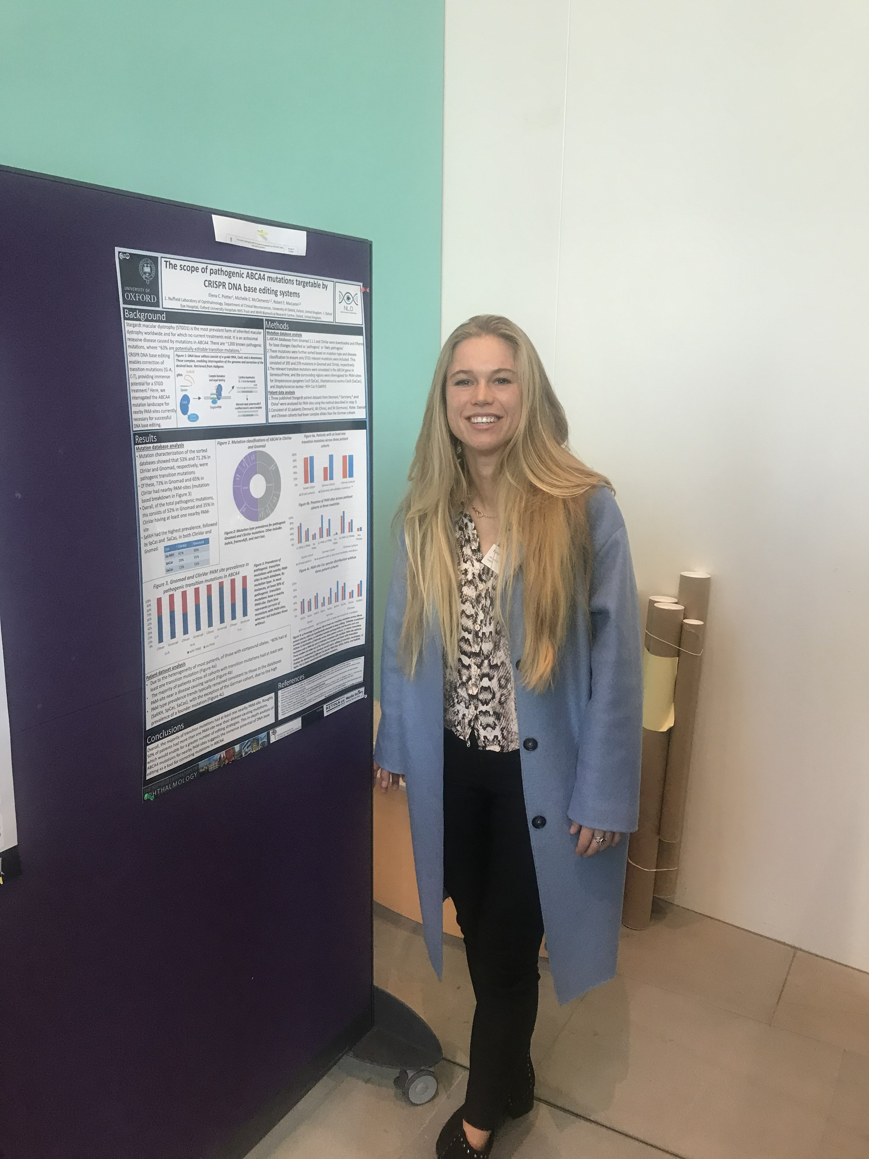 Elena Piotter, a white woman with long blonde hair, posing by a poster and smiling 