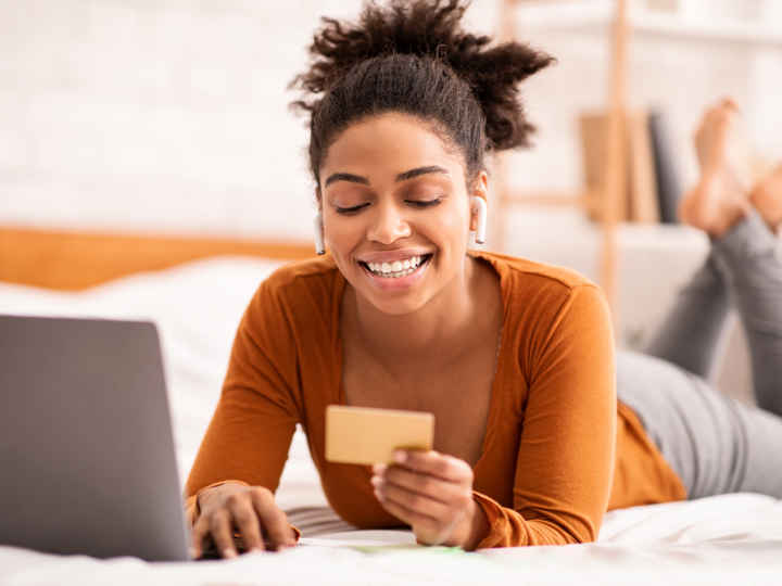 Woman on bed with laptop and credit card