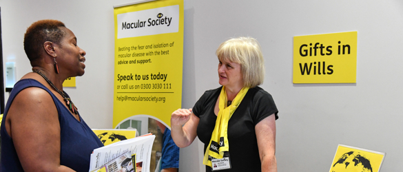 Conference delegate speaking with Macular Society staff at Gifts in Wills table
