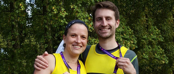 Two runners with vests and medals