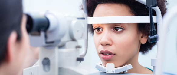 Woman having eye test, resting forehead and chin against machine.