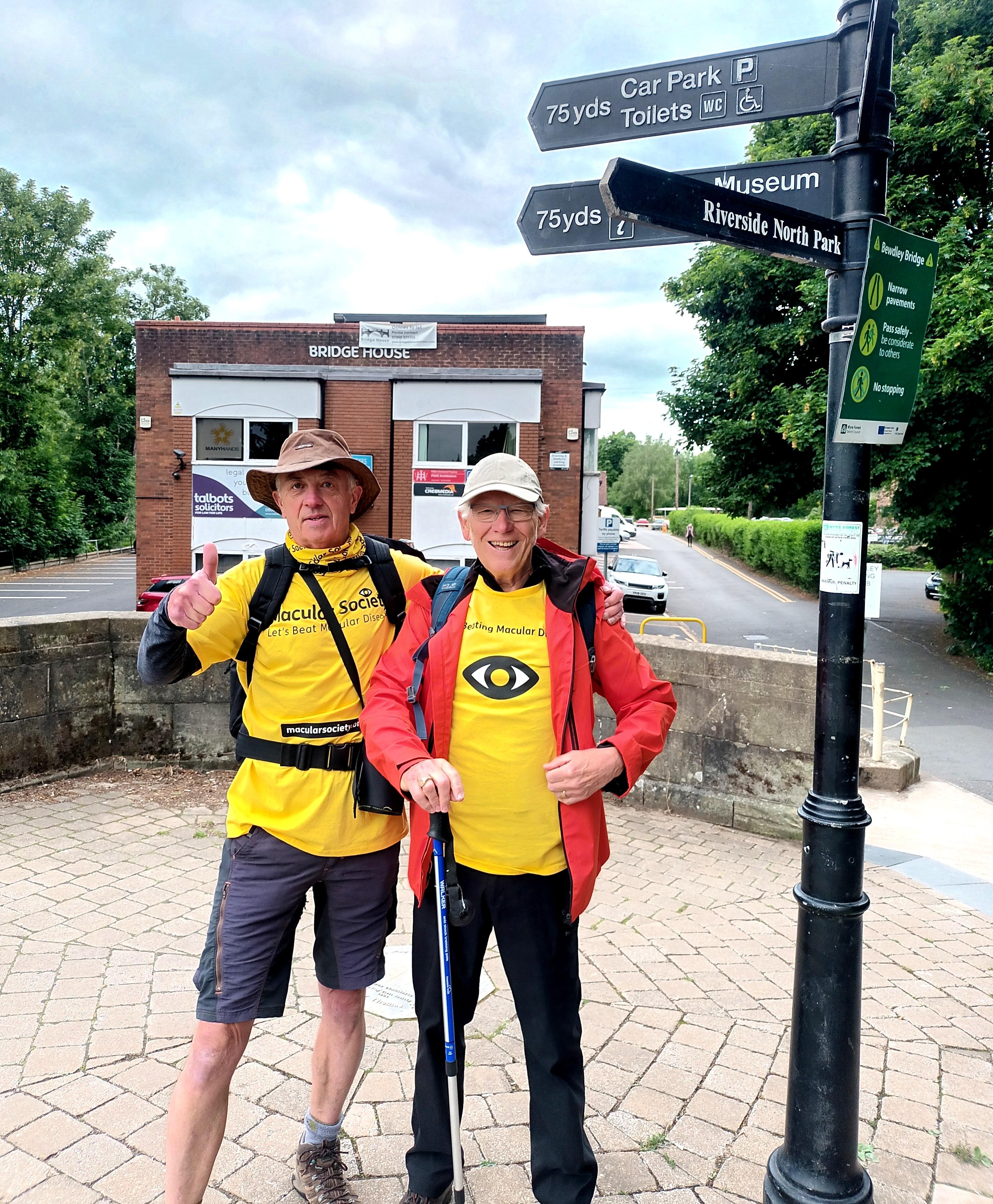 David and norman, two men in their 80s standing side by side in hats and yellow Macular Society tshirts. 