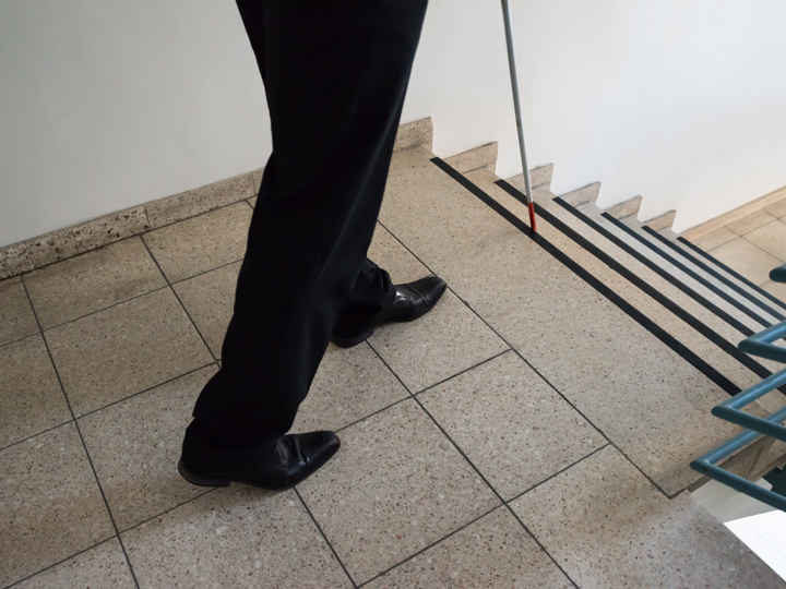 Person walking down the stairs with cane
