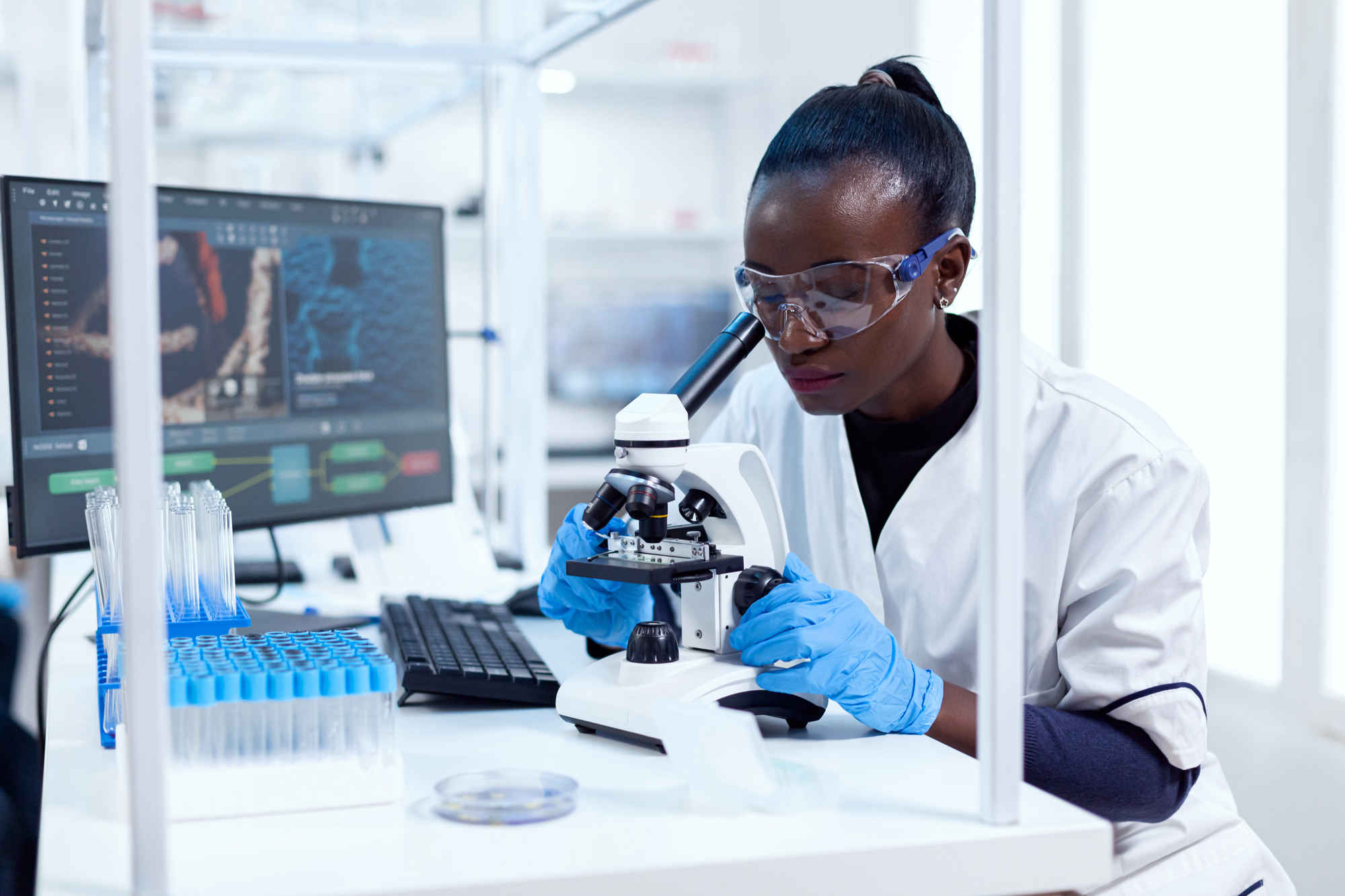 Researcher in laboratory looking into microscope