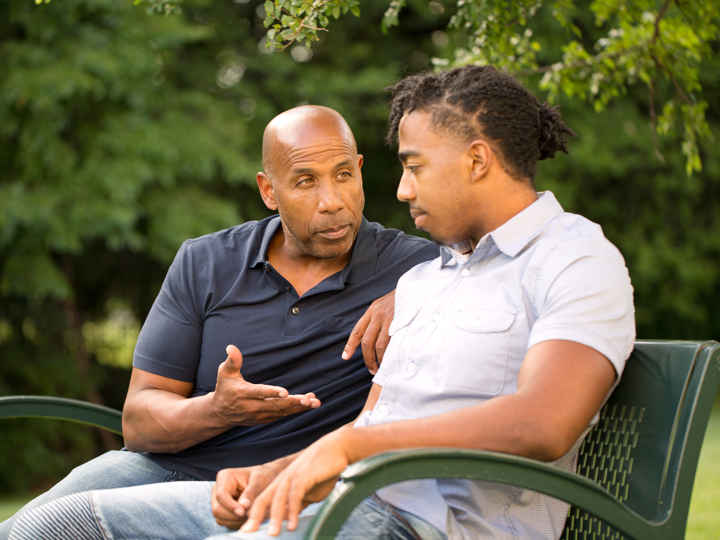 Man mentoring youth on park bench