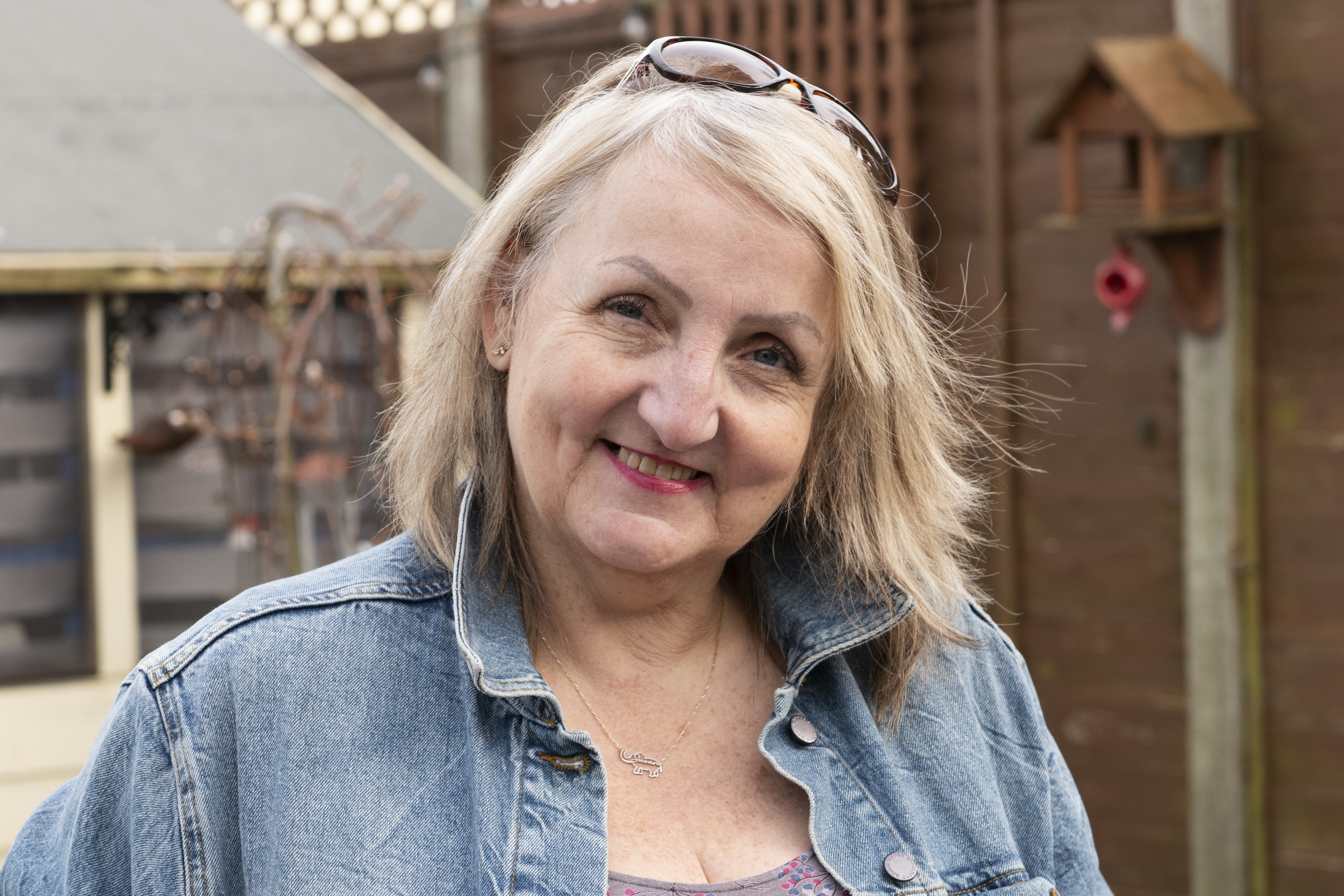 Sue a lady in her 60s with shoulder length blonde hair smiling to camera. 