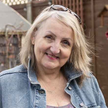 Sue a lady in her 60s with shoulder length blonde hair smiling to camera. 