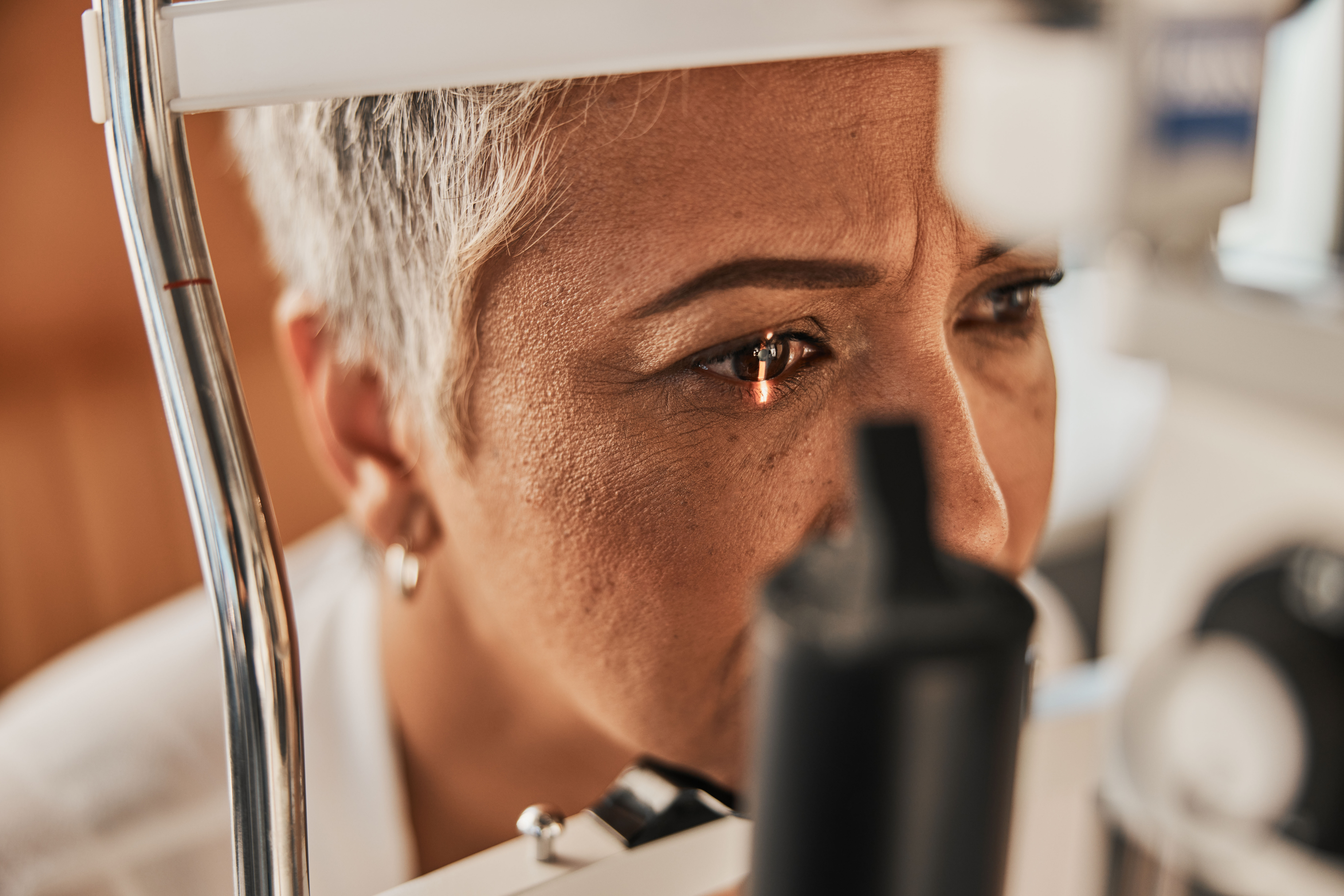 Older woman having her eyes checked, with light on her right eye