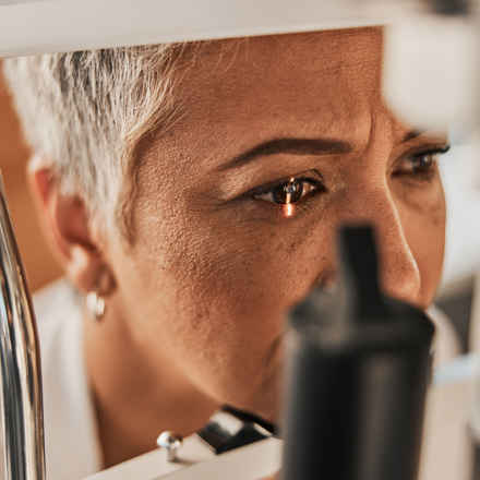 Older woman having her eyes checked, with light on her right eye