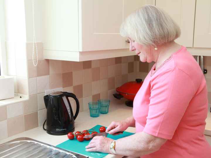 Older lady cutting food on chopping board