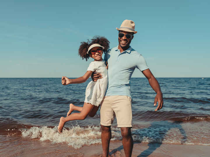 Father and daughter wearing sunglasses on beach
