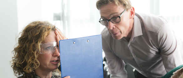 Skills for Seeing - woman wearing glasses with clip board, covering one eye, while a man oversees