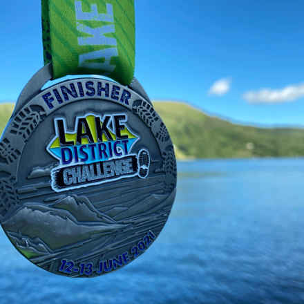 Lake District Ultra Challenge finisher medal with the water in the background